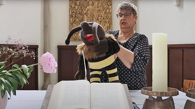 Pfarrerin Raneberg mit der Handpuppe "Biene Brumsel" vor dem Altar der Jakobi-Kirche